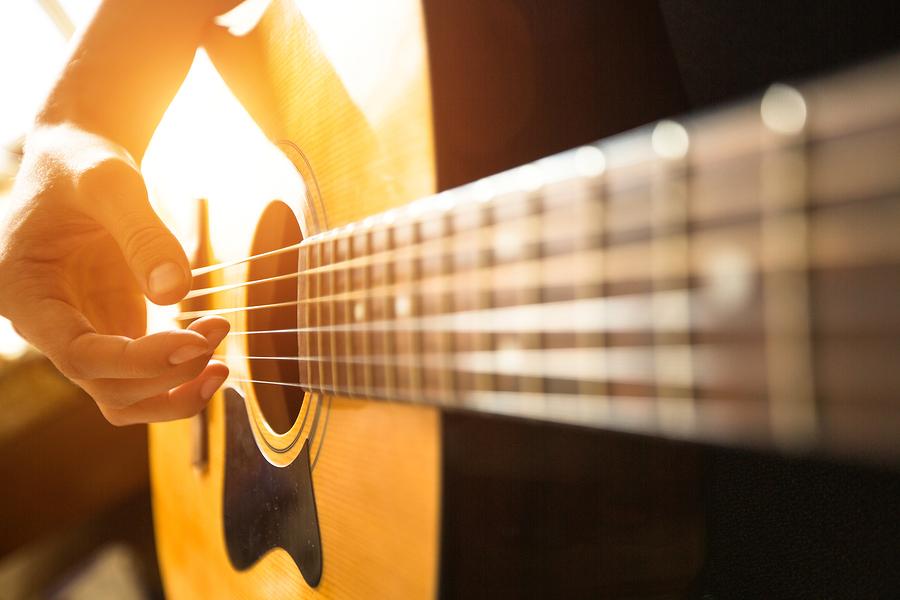 Female hand close-up playing on acoustic guitar.